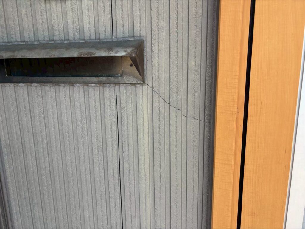 【クラック｜ポスト周辺】<br />
ポスト周辺には外壁のクラックが確認できました。ひび割れは大きさや位置によって必要な対応が異なります。今回は状態を確認したうえで下地を処理し、傷んだ部分をそのまま残さず塗装工程へ進みました。